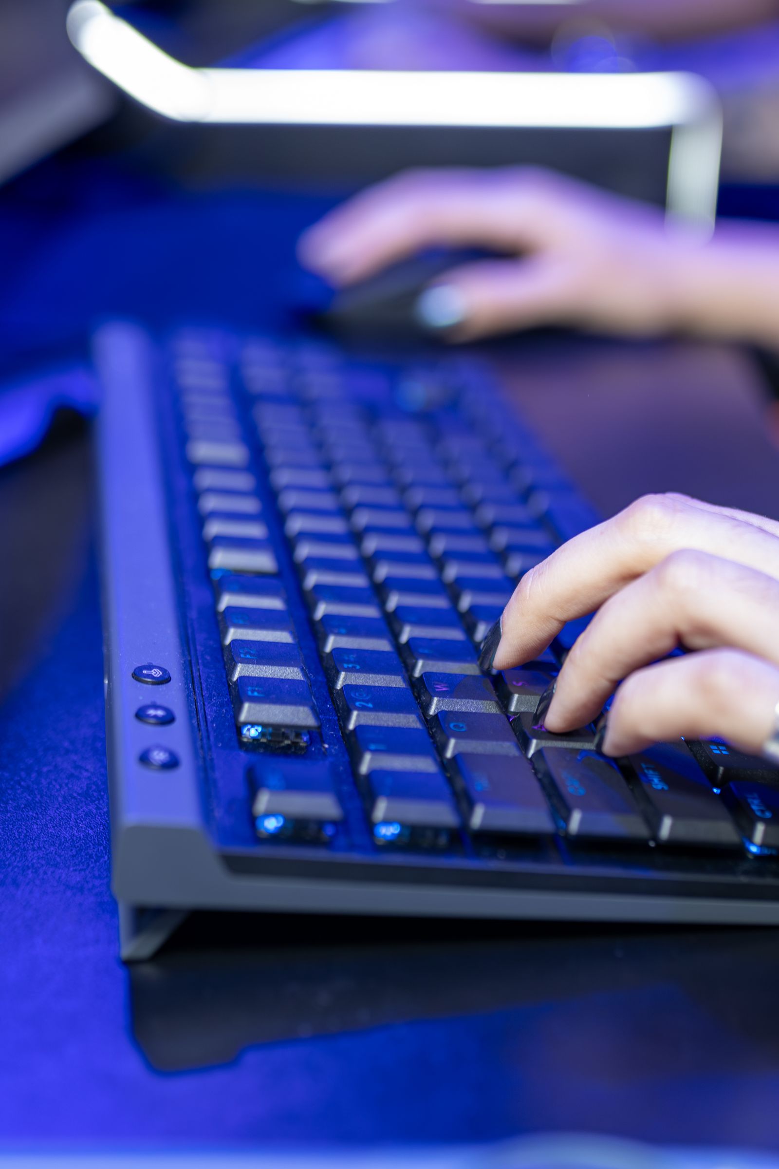 Close-up of hands typing on a backlit keyboard